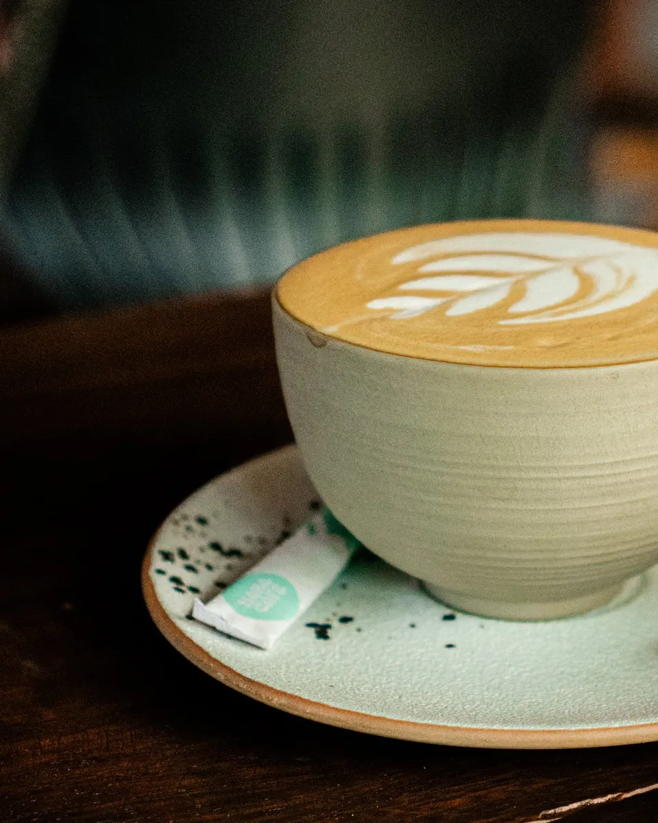 A latte with leaf art on the wooden table